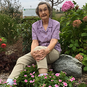 Carol Jackubs Image of Carol Jackubs sitting in a bed of flowers