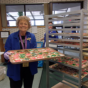 woman holding tray of decorated cookies