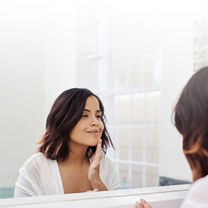 woman_in_mirror woman applying skin care product in mirror